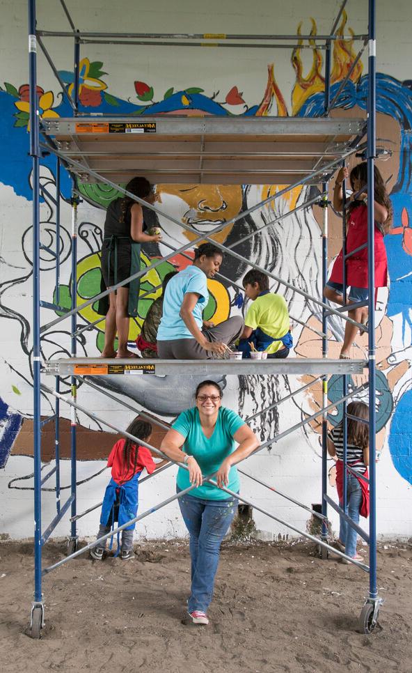 A group of people in front of an in-progress mural